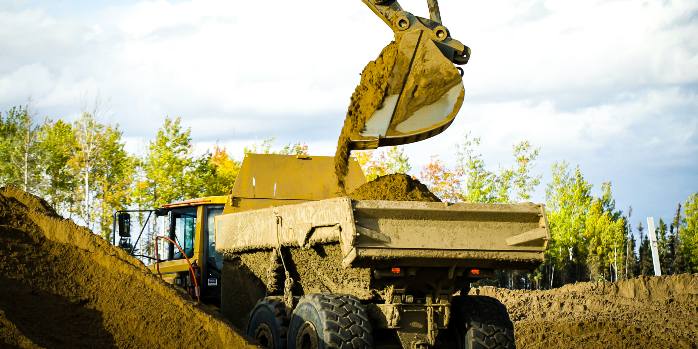 Dump truck being loaded by excavator during roadbuilding project